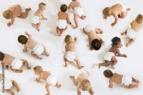 Foto Group of multiethnic babies crawling isolated on white background