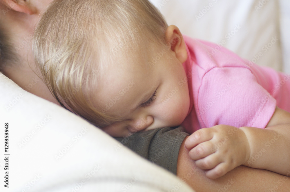 Closeup of a baby sleeping on mother's shoulder