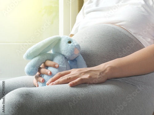 Pregnancy concept. Pregnant woman is playing the rabbit doll in her hand.