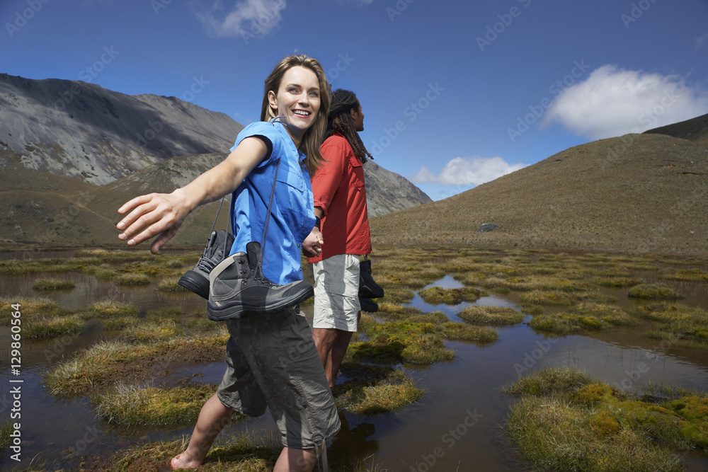 Man and happy woman walking through pond against hills