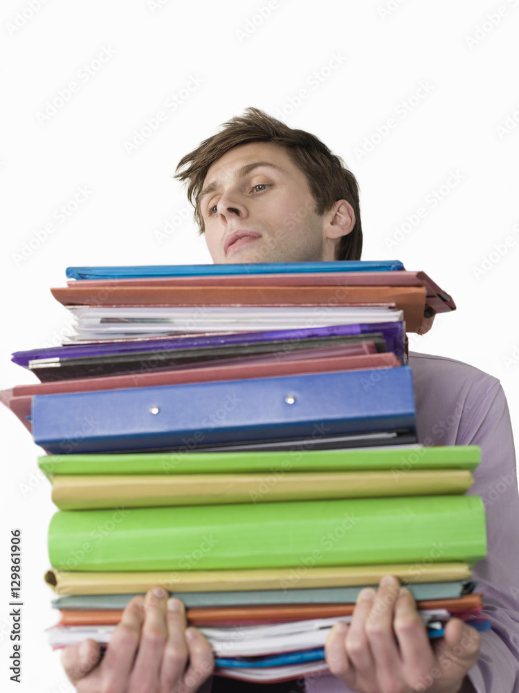 Male office worker carrying heavy binders against white background Male office worker carrying heavy binders against white background