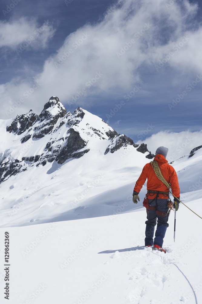 Rear view of a male hiker connected to safety line in snowy mountains