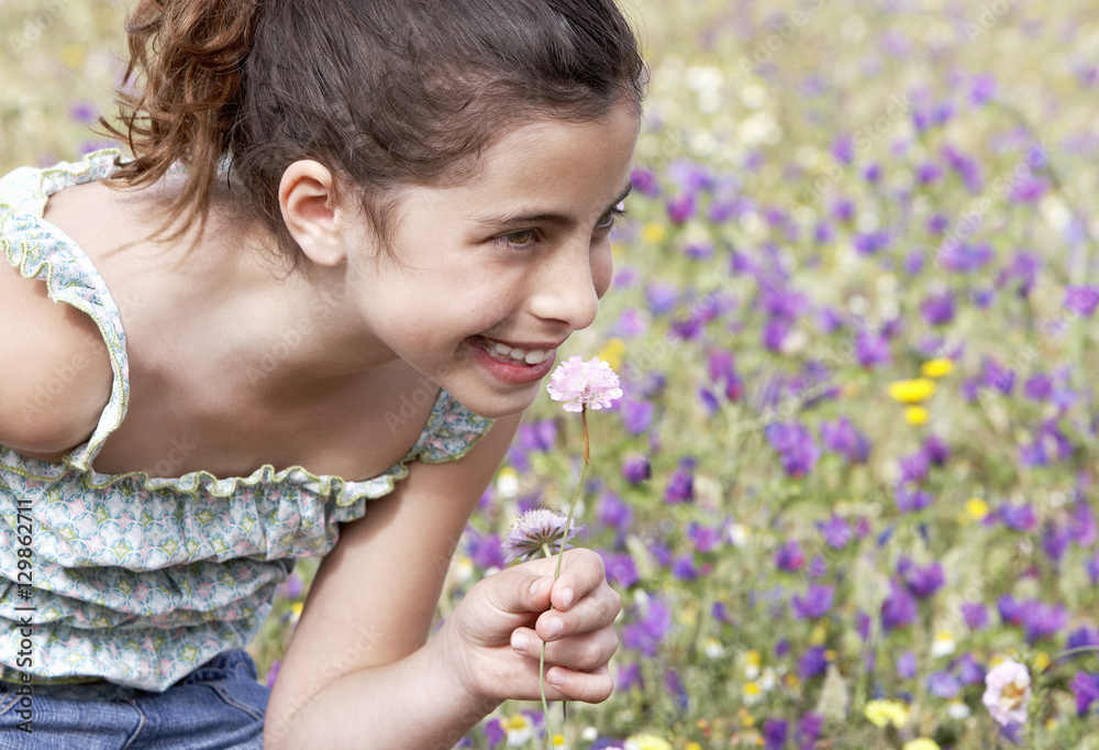 Closeup of happy cute little girl smelling flower at field Closeup of happy cute little girl smelling flower at field