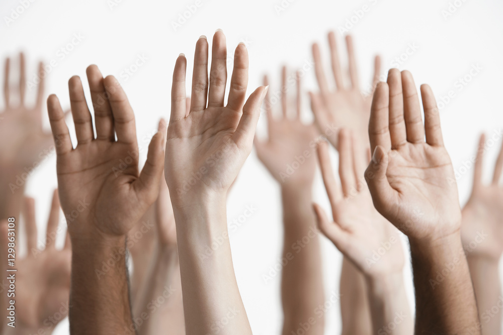Closeup of multiethnic men and women raising hands against white background Closeup of multiethnic men and women raising hands against white background
