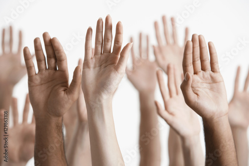 Closeup of multiethnic men and women raising hands against white background