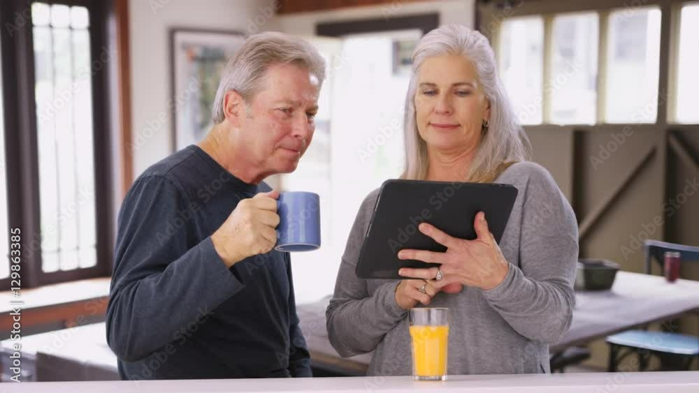 Elderly caucasian couple looking at tablet computer during breakfast Elderly caucasian couple looking at tablet computer during breakfast