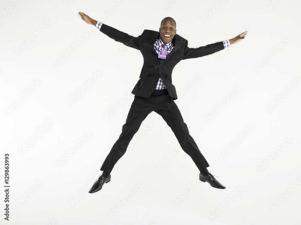 Full length portrait of a bald businessman jumping in star shape against white background
