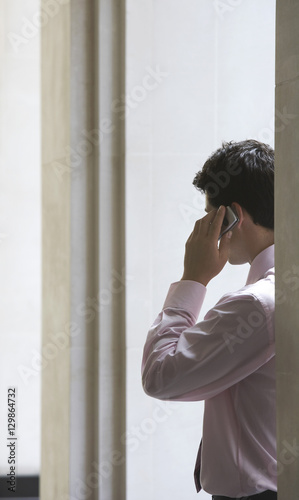 Rear view of young businessman using mobile phone
