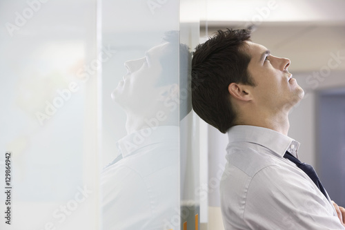 Unhappy businessman leaning back against office wall and looking at ceiling photo