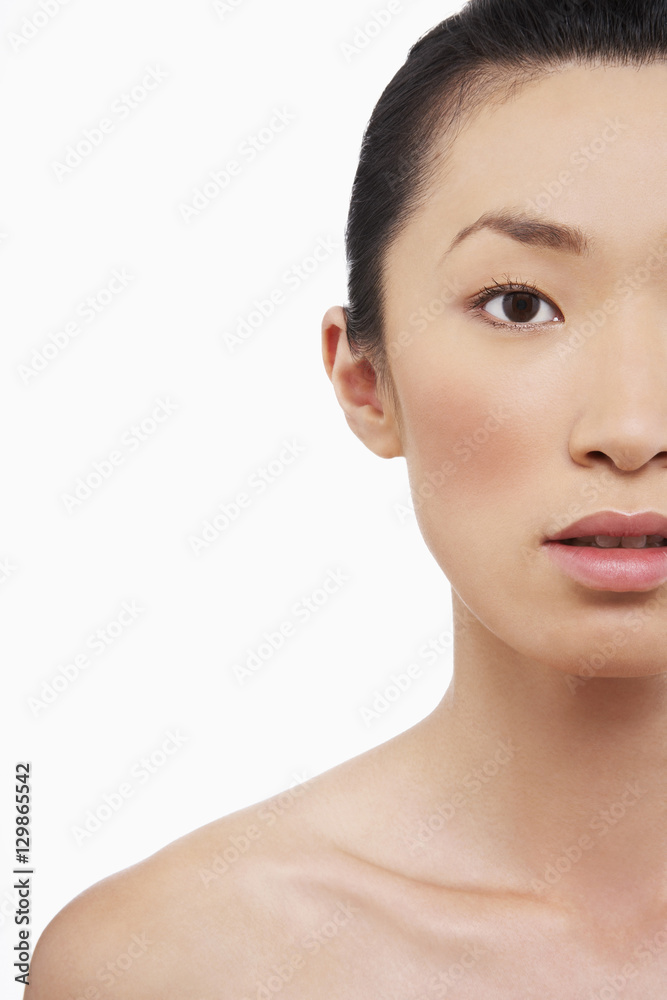 Closeup of young Asian woman with blank expression on white background