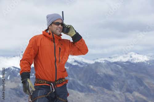 Male hiker using walkie talkie against mountain peaks photo