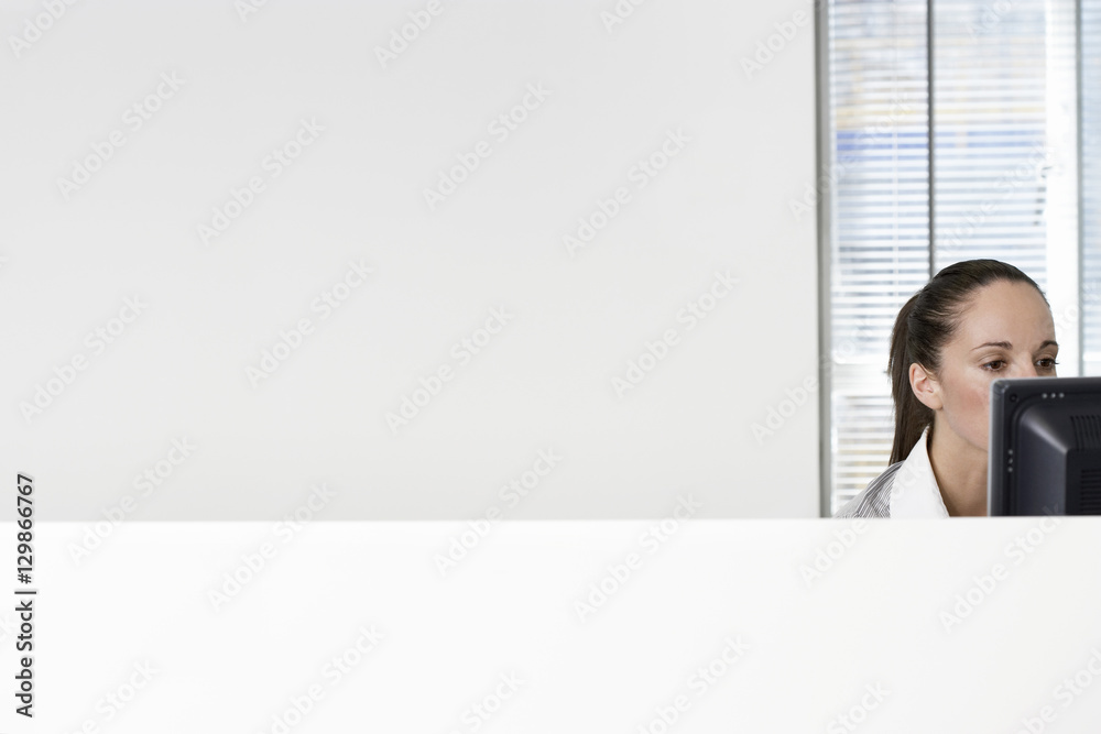 Serious young businesswoman using computer in office cubicle Serious young businesswoman using computer in office cubicle