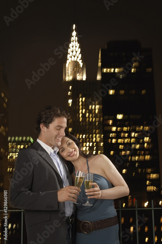 Young couple toasting champagne against New York skyline at night
