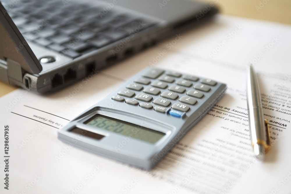 Calculator lying next to laptop close-up Calculator lying next to laptop close-up
