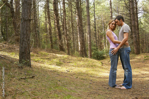 Full length side view of a romantic couple standing in forest