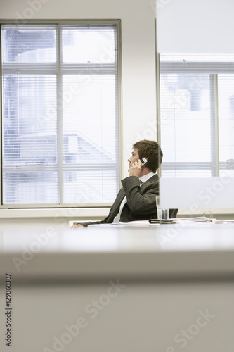 Businessman sitting at office desk and using cellphone