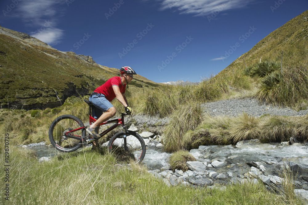 Side view of a male cyclist riding through rocky field
