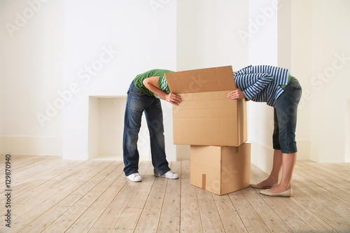 Cuadro en lienzo Young couple searching into cardboard box in new home