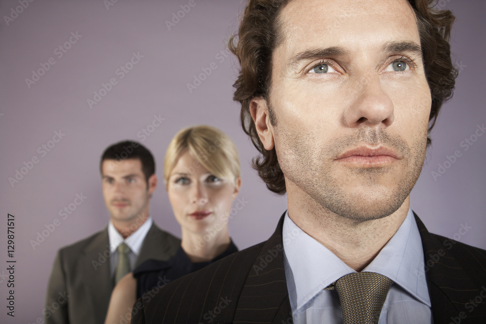 Closeup of a businessman with two colleagues in background Closeup of a businessman with two colleagues in background