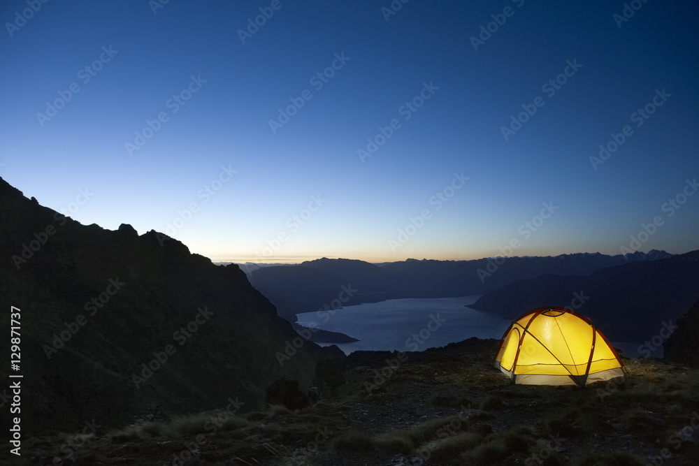 Illuminated tent by the lakeshore at dusk - obrazy, fototapety, plakaty 
