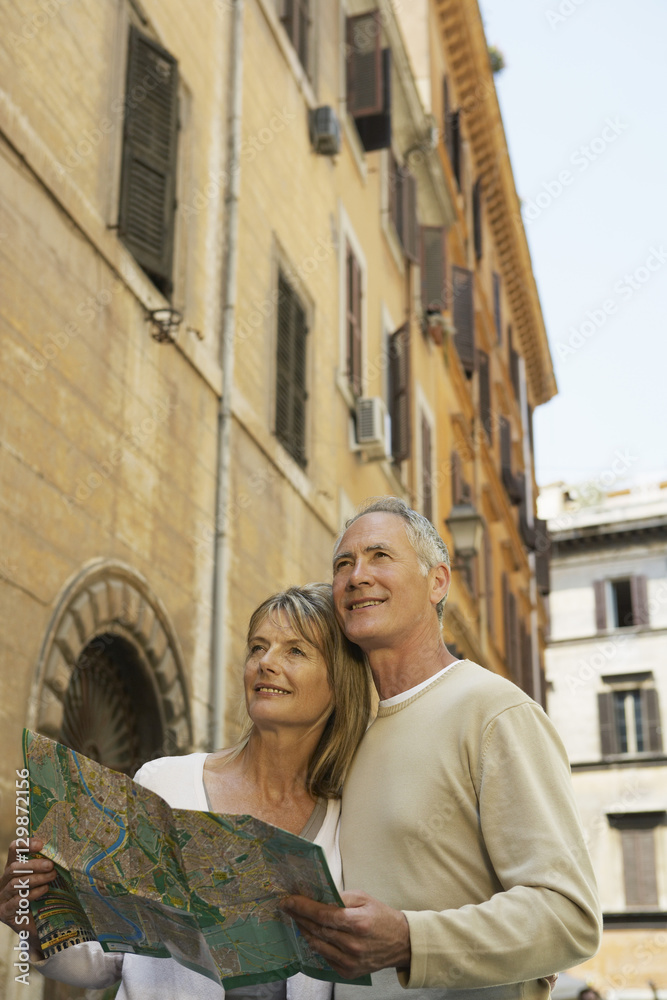 Happy couple holding map on street in Rome, Italy