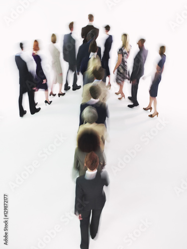 Blurred group of multiethnic businesspeople in arrow formation against white background