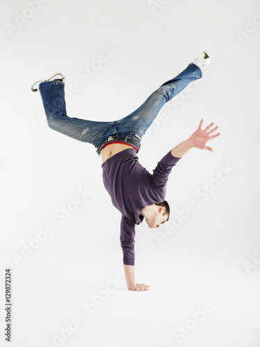 Canvastavla Full length of a young man doing one handed handstand against gray background