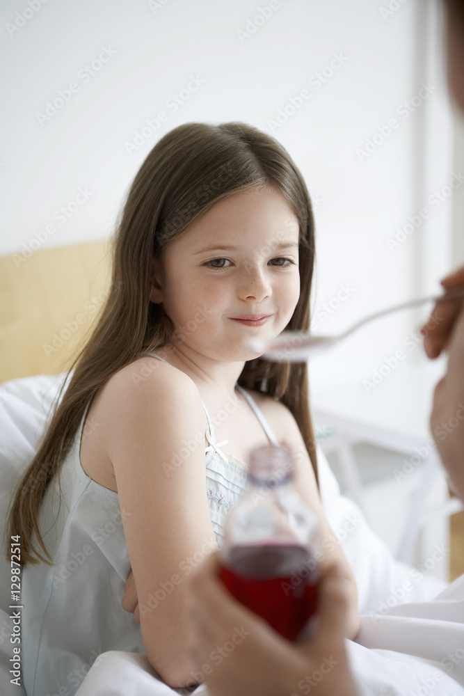 Mother giving cough syrup to daughter in bed Mother giving cough syrup to daughter in bed