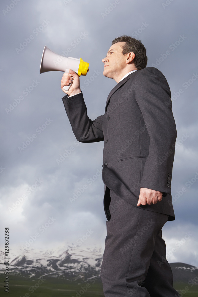 Low angle view of businessman speaking through megaphone in mountain field Low angle view of businessman speaking through megaphone in mountain field
