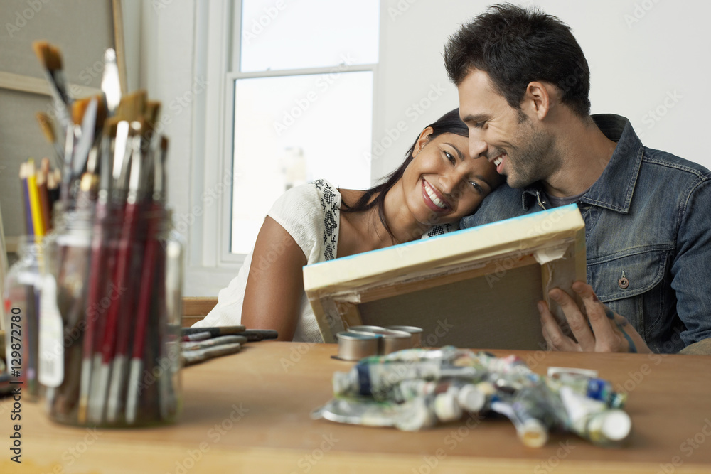 Happy young couple looking at painting in artist studio