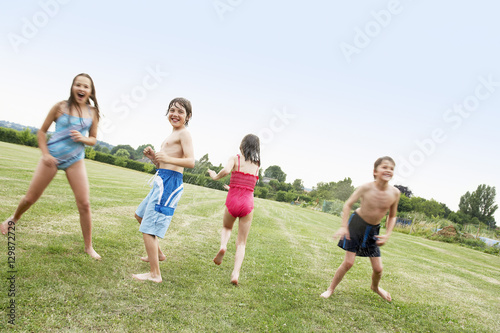 Full length of boys and girls in swimsuits playing on field