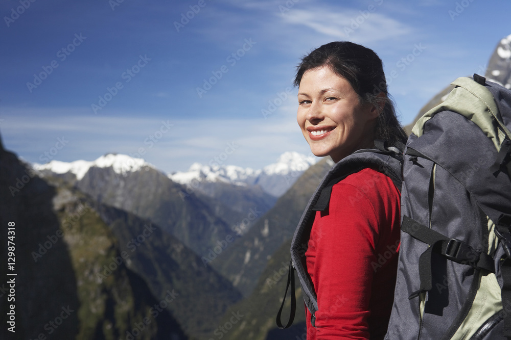 Portrait of a female hiker with backpack against mountain peaks