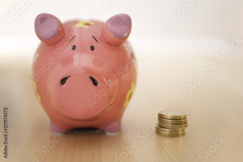 Stack of gold coins standing next to piggy bank