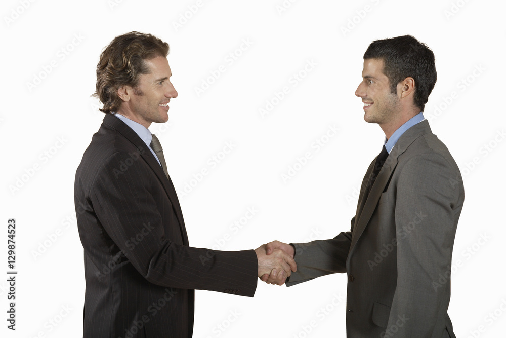 Side view of two young businessmen shaking hands on white background Side view of two young businessmen shaking hands on white background