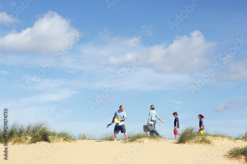 Side view of family walking sand dune on beach against the sky