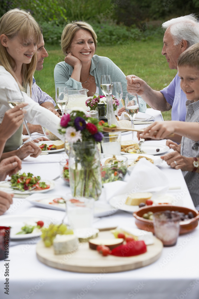 Smiling middle aged woman dining with family in garden Smiling middle aged woman dining with family in garden