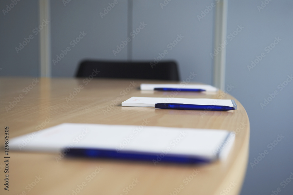Selective focus of notepad and pens on conference table Selective focus of notepad and pens on conference table
