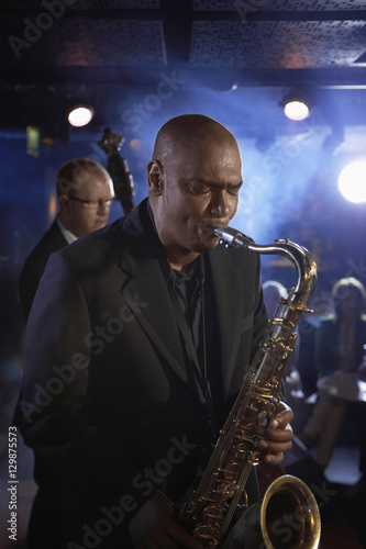 Saxophone player with man playing double bas in background on stage