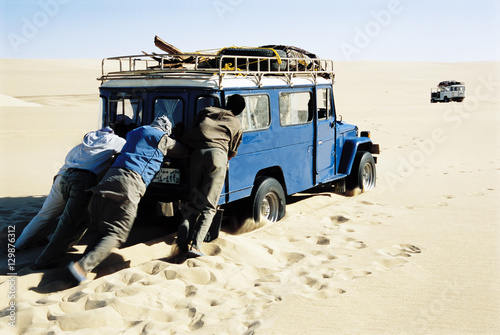 Papier peint Men pushing jeep in desert
