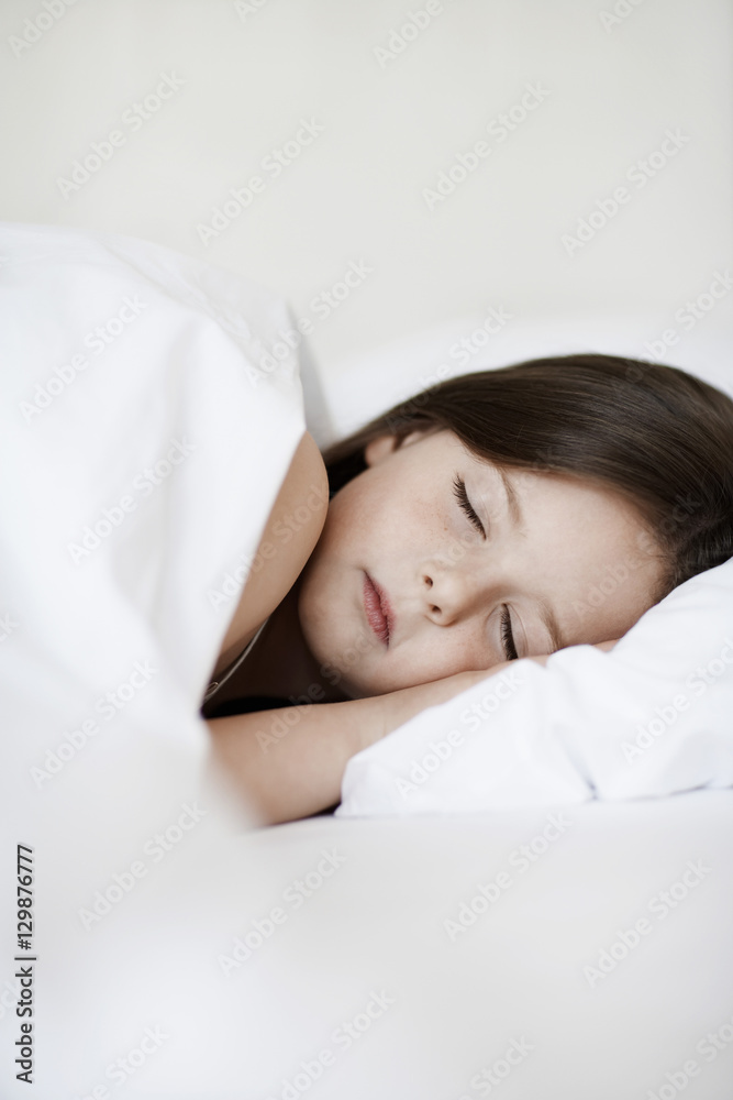 Little girl sleeping in bed cover with white blanket