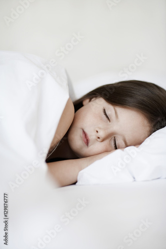Little girl sleeping in bed cover with white blanket