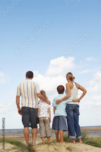 Rear view of a family standing on sand and looking at view on beach