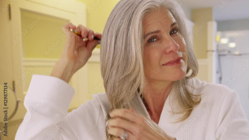 Closeup portrait of a mid aged woman combing her hair Closeup portrait of a mid aged woman combing her hair