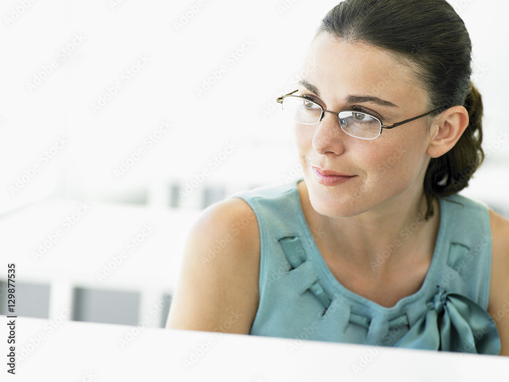 Thoughtful young businesswoman looking away in office Thoughtful young businesswoman looking away in office