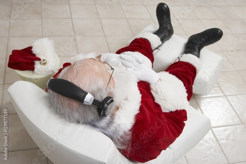 High angle view of relaxed Santa Claus listening music