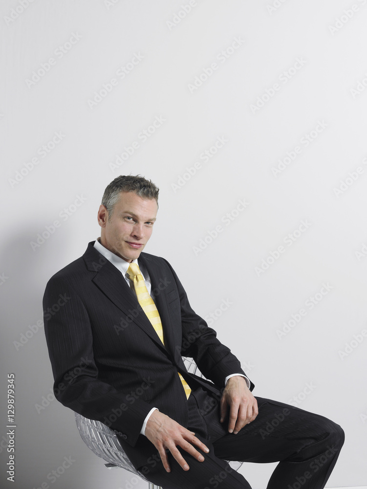 Portrait of a confident businessman sitting in swivel chair against gray background Portrait of a confident businessman sitting in swivel chair against gray background