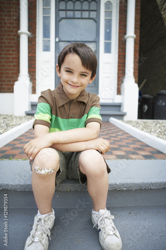 Portrait of happy little boy sitting on front steps of house © moodboard