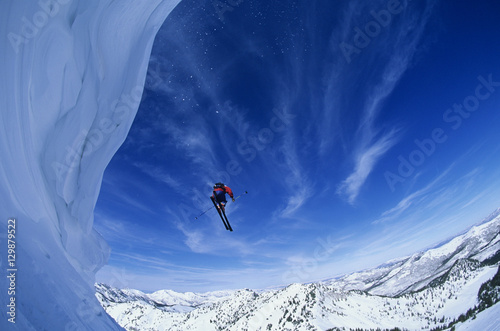 Low angle view of man jumping from mountain ledge against sky © moodboard