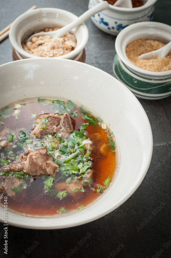 Asian style pork bone soup with seasoning on dark stone background Asian style pork bone soup with seasoning on dark stone background
