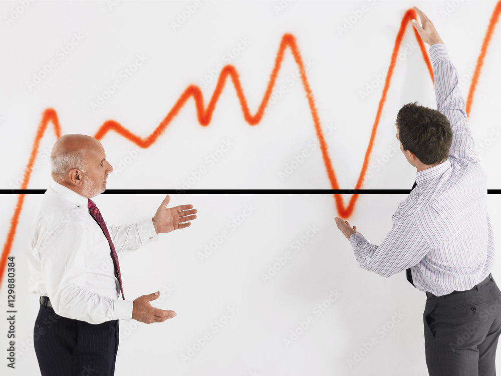Young male executive explaining graph to mature businessman Young male executive explaining graph to mature businessman